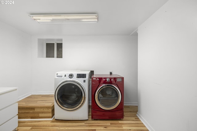 laundry area with separate washer and dryer and light hardwood / wood-style floors