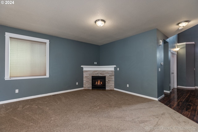 unfurnished living room with a fireplace, dark hardwood / wood-style flooring, and a textured ceiling