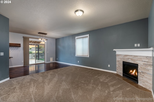 unfurnished living room with dark wood-type flooring, a stone fireplace, and a textured ceiling