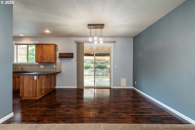 kitchen with dark hardwood / wood-style flooring, pendant lighting, a wealth of natural light, and kitchen peninsula