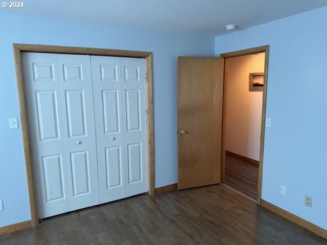 unfurnished bedroom with dark hardwood / wood-style flooring and a closet