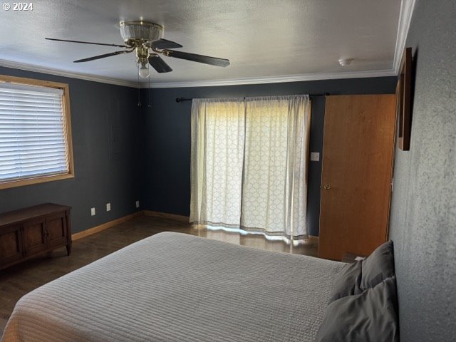 bedroom featuring dark wood-type flooring, ornamental molding, and ceiling fan