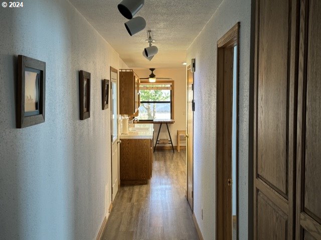 hallway with hardwood / wood-style flooring and a textured ceiling