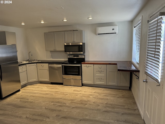 kitchen with appliances with stainless steel finishes, gray cabinets, sink, and an AC wall unit