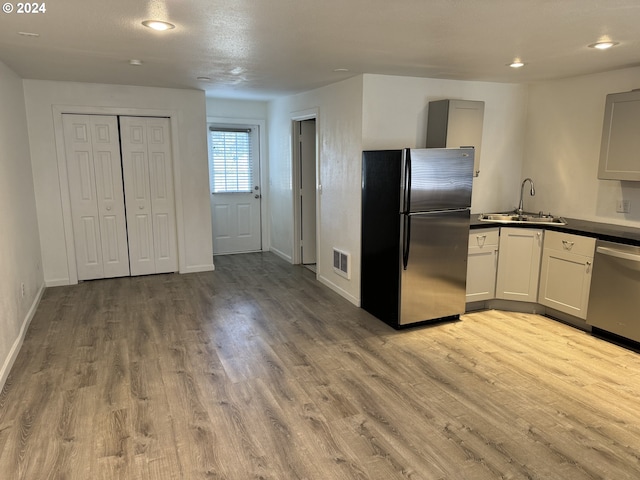 kitchen featuring stainless steel appliances, white cabinetry, sink, and light wood-type flooring