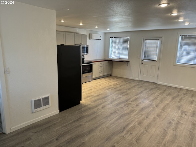 kitchen with stainless steel appliances, a wall mounted AC, and light wood-type flooring