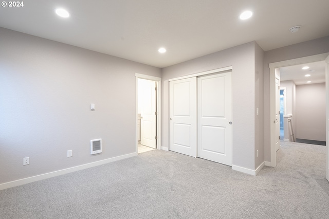 unfurnished bedroom with light carpet and a closet