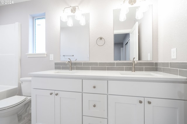 bathroom featuring vanity, toilet, and tasteful backsplash