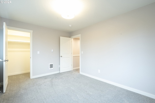 unfurnished bedroom with carpet, a spacious closet, and a closet