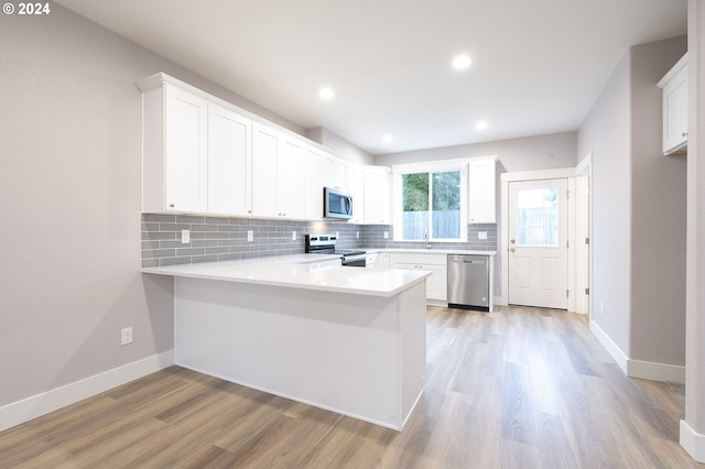 kitchen featuring kitchen peninsula, light hardwood / wood-style flooring, white cabinets, and appliances with stainless steel finishes