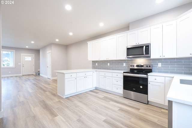 kitchen featuring kitchen peninsula, appliances with stainless steel finishes, backsplash, light hardwood / wood-style flooring, and white cabinetry