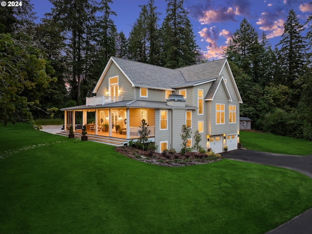 view of front of house with a balcony, a garage, covered porch, and a yard