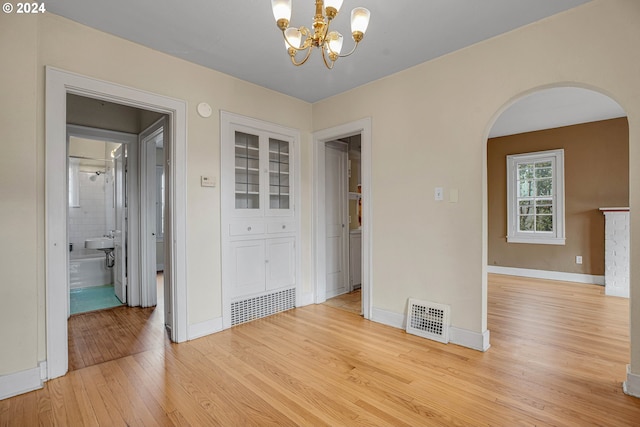 1175 Hines St SE, Salem, OR 97302 - spare room featuring arched walkways, light wood-style floors, a chandelier, and baseboards