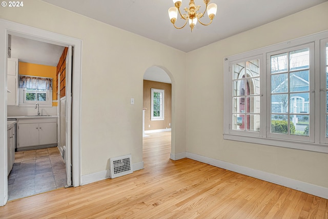 1175 Hines St SE, Salem, OR 97302 - empty room featuring arched walkways, a chandelier, baseboards, and light wood-style floors