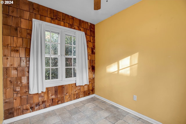1175 Hines St SE, Salem, OR 97302 - spare room featuring wood walls, baseboards, ceiling fan, and stone finish floors