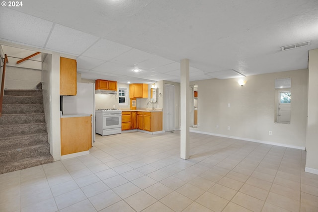 interior space featuring a paneled ceiling, light tile patterned floors, and white range