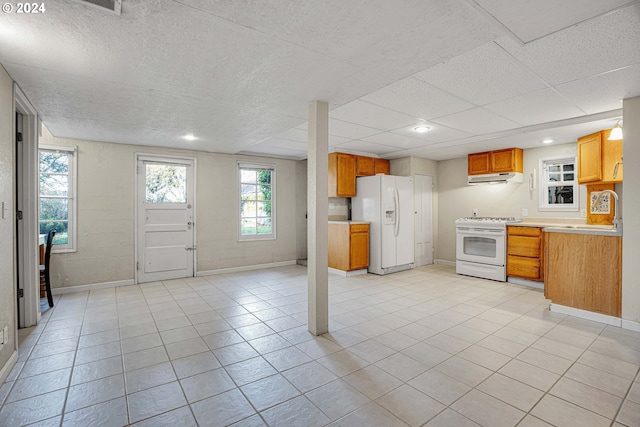 kitchen with sink, white appliances, exhaust hood, and light tile patterned floors