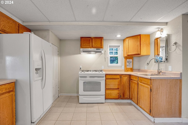 kitchen with a paneled ceiling, sink, light tile patterned flooring, and white appliances