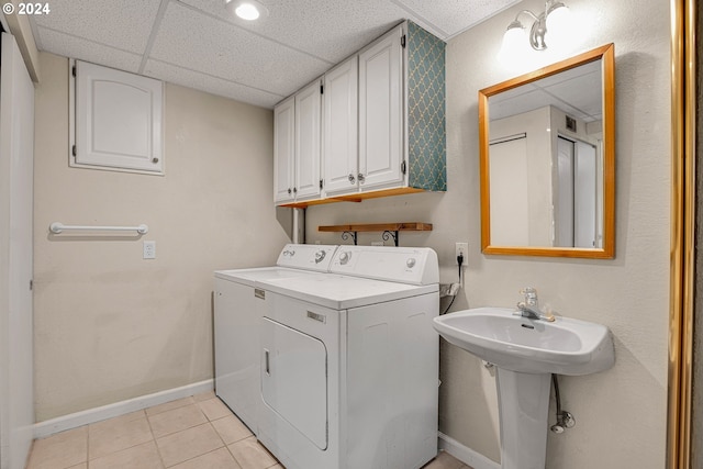 clothes washing area featuring cabinets, independent washer and dryer, and light tile patterned floors