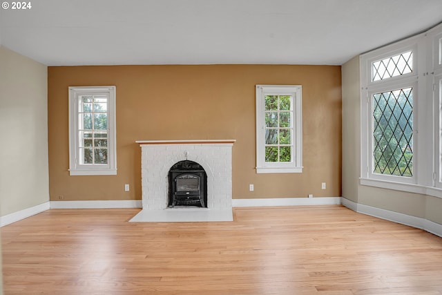 unfurnished living room with a wood stove, a wealth of natural light, and light wood-type flooring