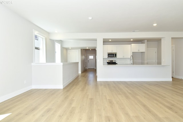 unfurnished living room with sink and light wood-type flooring