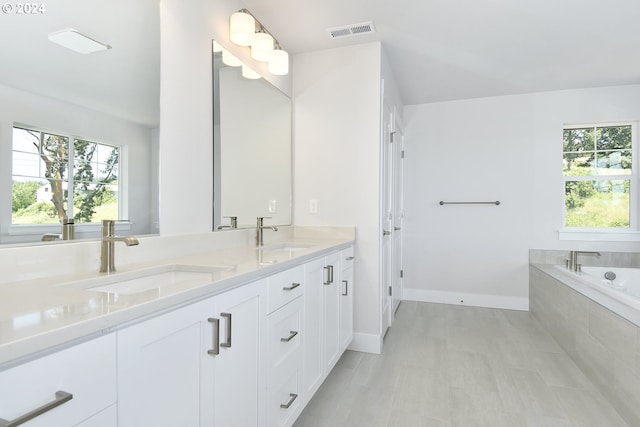 bathroom with vanity and tiled tub