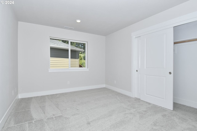 unfurnished bedroom featuring light colored carpet and a closet