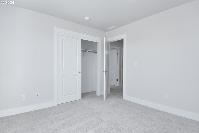 unfurnished bedroom featuring light carpet and a closet