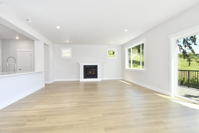 unfurnished living room with light wood-type flooring and plenty of natural light