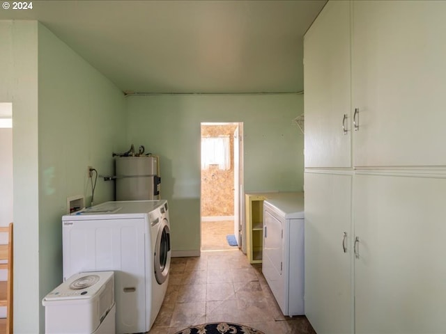 washroom with secured water heater, washer and clothes dryer, light tile patterned floors, and cabinets