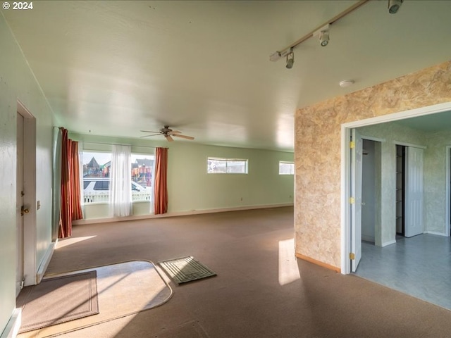 empty room featuring carpet flooring, track lighting, and ceiling fan