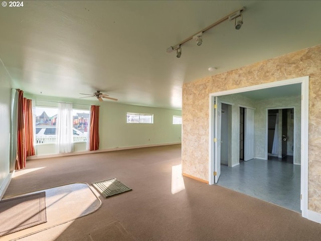 empty room featuring carpet flooring, track lighting, and ceiling fan