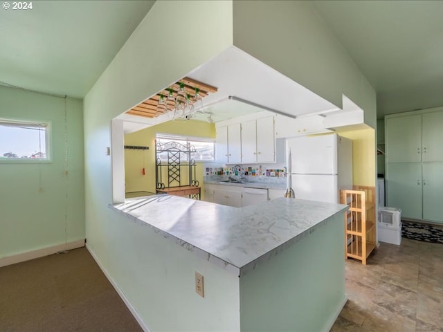 kitchen with white appliances, white cabinetry, kitchen peninsula, and a wealth of natural light