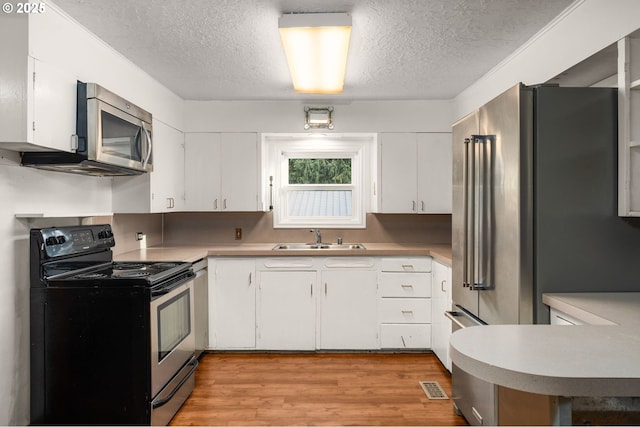 kitchen featuring a textured ceiling, sink, white cabinetry, and stainless steel appliances