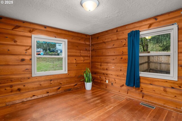 dining space with hardwood / wood-style floors, a textured ceiling, and wood walls