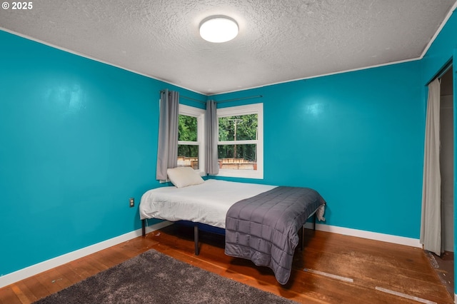 bedroom with dark hardwood / wood-style floors and a textured ceiling