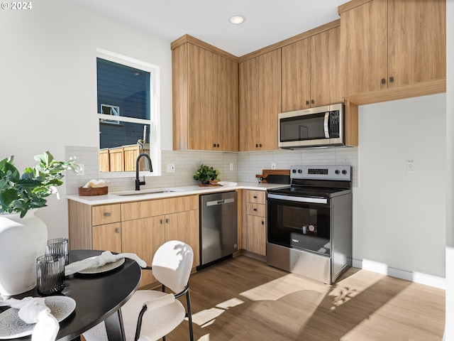 2519 NE Killingsworth St Unit 1, Portland, OR 97211 - kitchen with appliances with stainless steel finishes, a sink, wood finished floors, tasteful backsplash, and recessed lighting