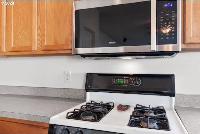 kitchen featuring light countertops, stainless steel microwave, and white range with gas cooktop