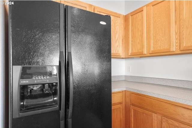 kitchen with light countertops and black refrigerator with ice dispenser