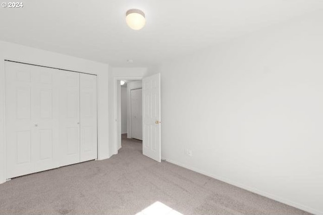 unfurnished bedroom featuring light colored carpet and a closet