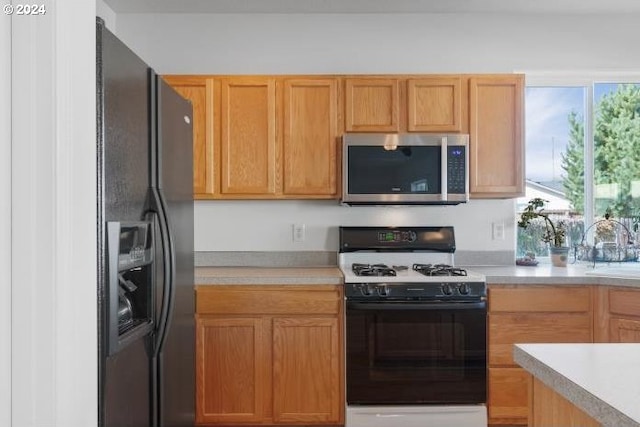 kitchen with range with gas cooktop, black refrigerator with ice dispenser, and sink