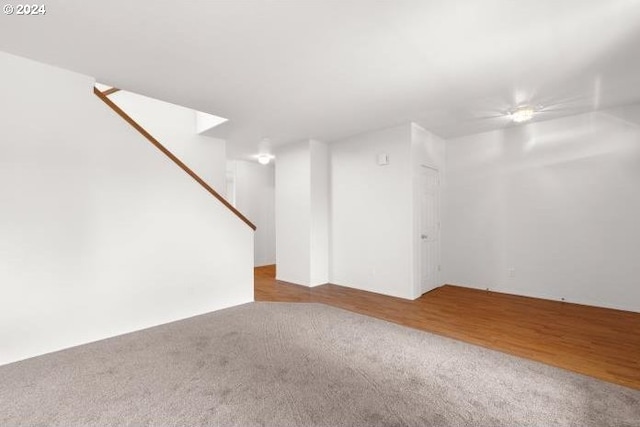 unfurnished living room with carpet flooring, stairs, and a ceiling fan