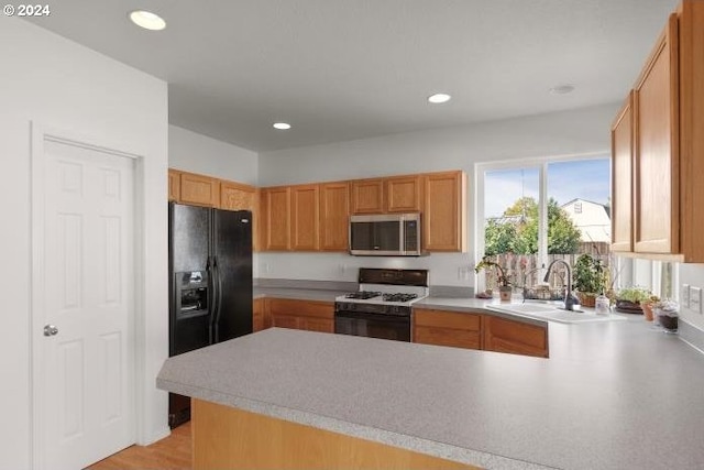 kitchen with kitchen peninsula, black refrigerator with ice dispenser, sink, and white gas stove