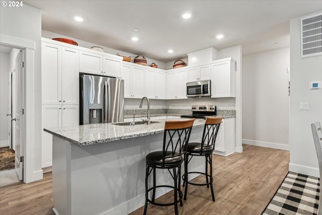 kitchen featuring sink, stainless steel appliances, light hardwood / wood-style floors, a kitchen island with sink, and white cabinets