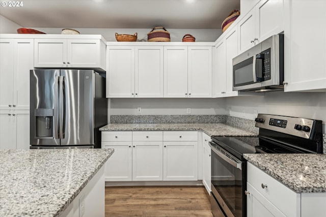 kitchen featuring light stone countertops, light wood-type flooring, stainless steel appliances, and white cabinetry