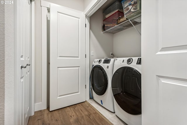 laundry area with washer and clothes dryer and light wood-type flooring