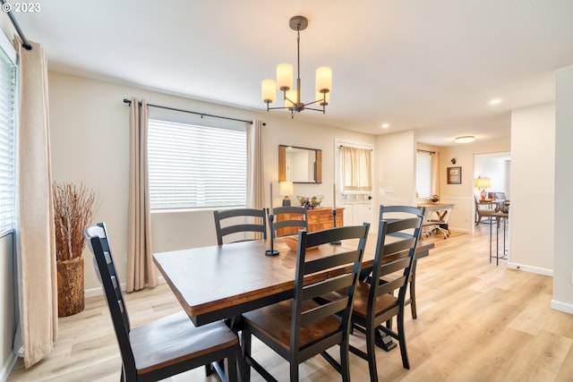 dining space with light hardwood / wood-style flooring and a chandelier