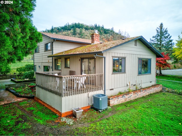 back of property featuring central air condition unit and a lawn