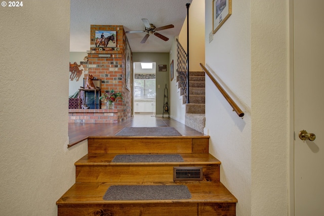 stairs with a textured ceiling, tile patterned floors, and ceiling fan