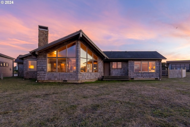 back house at dusk featuring a yard